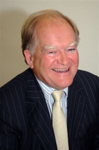 A portrait photo of a man in a shirt, tie and jacket, smiling