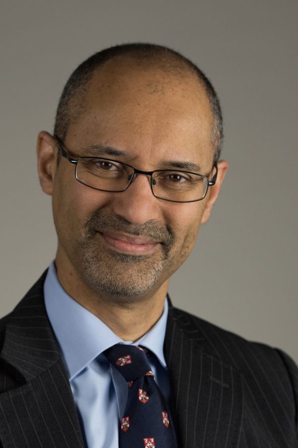 Portrait photograph of a man in a suit jacket and tie wearing glasses