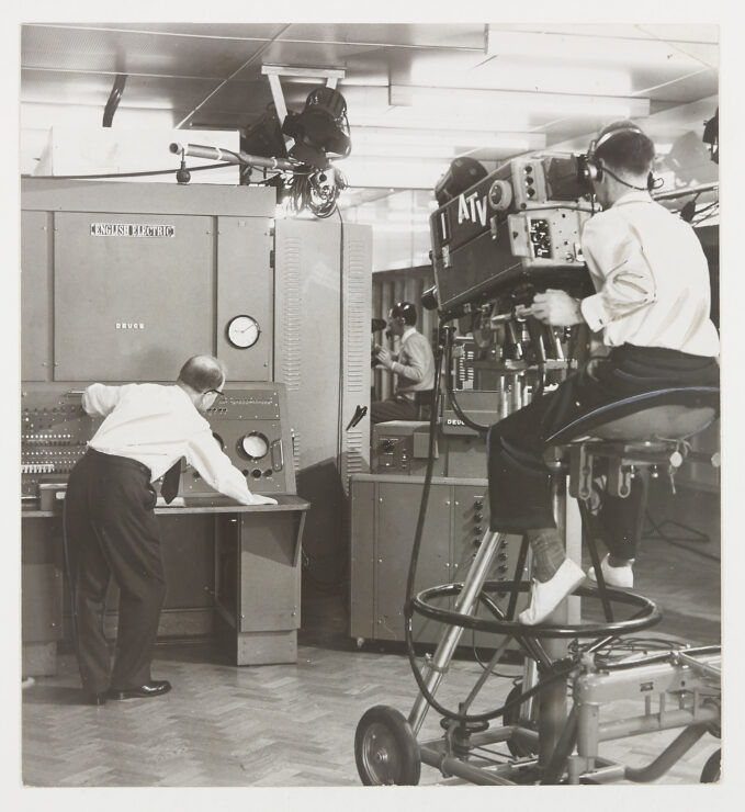 A large computer with the label English Electric being filmed by a large ATV camera operated by a man.