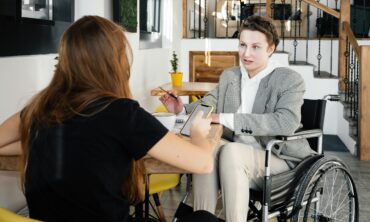woman using a wheelchair communicating with a female colleague in a cafe