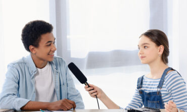 Two children, one with a microphone, interviewing the other.
